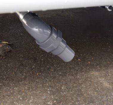 Grey wastewater pipe beneath a Carado motorhome, detail view