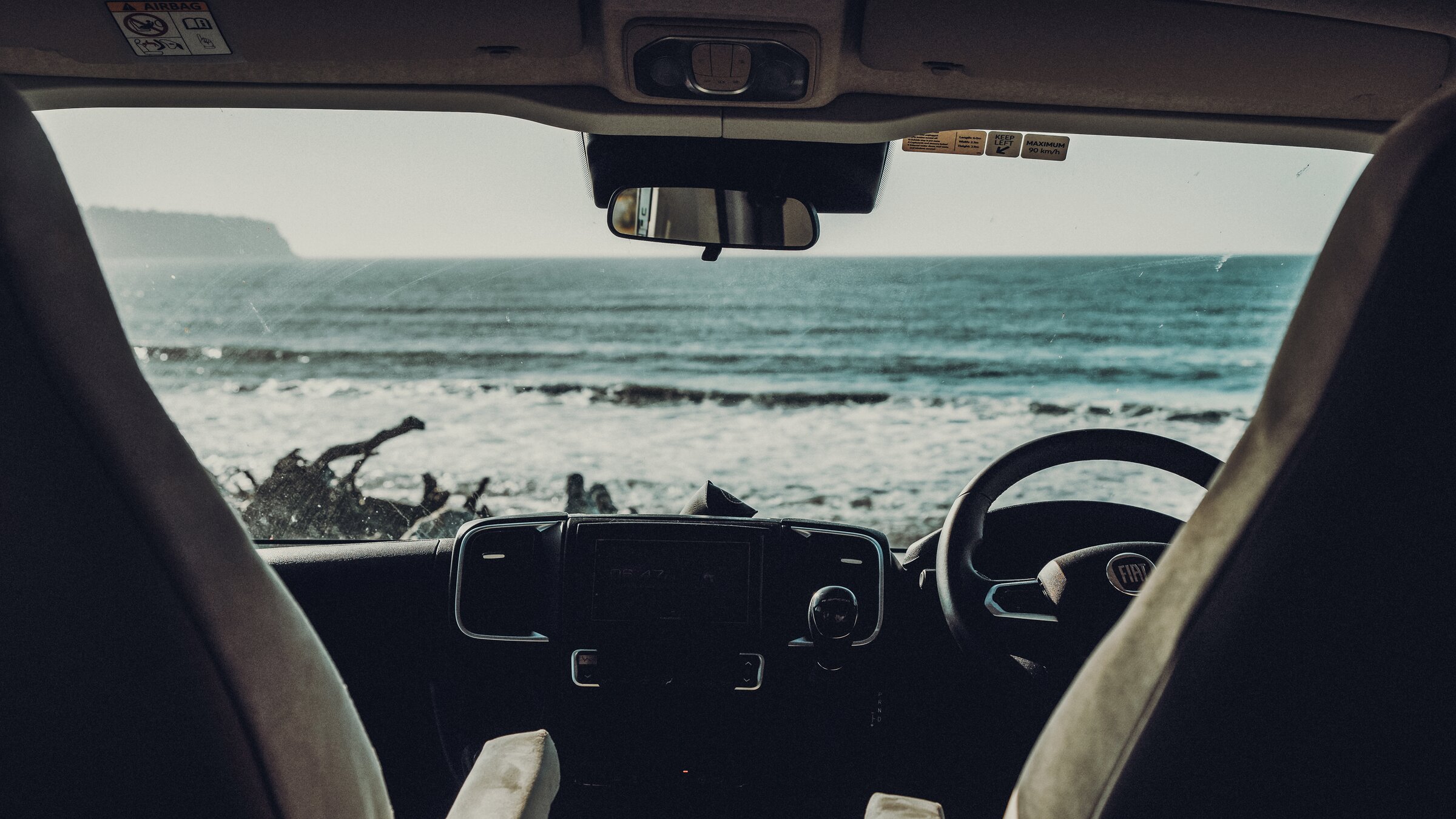 Blick aus dem Fahrerhaus eines Carado Wohnmobils auf Meer und Strand