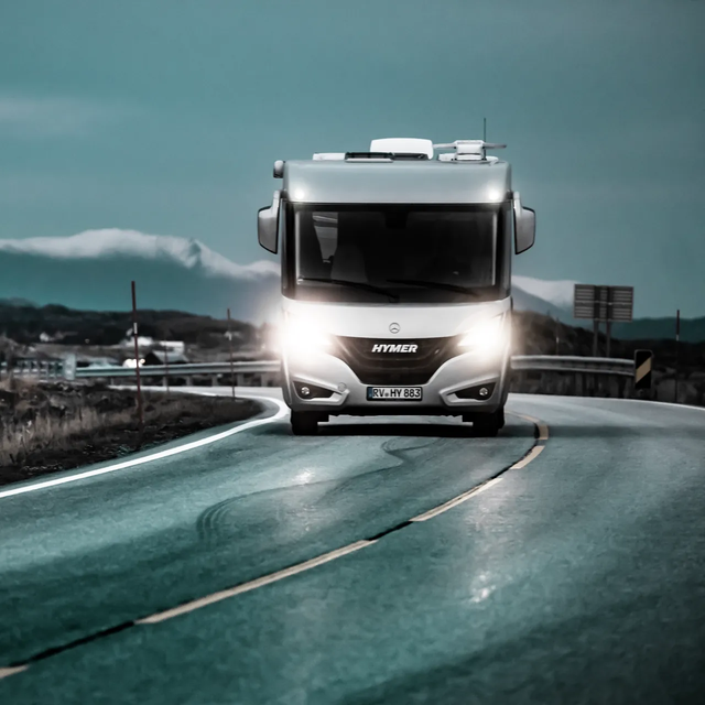 Verlichte, rijdende HYMER B-ML I camper op een gladde weg bij schemering op een Atlantische weg