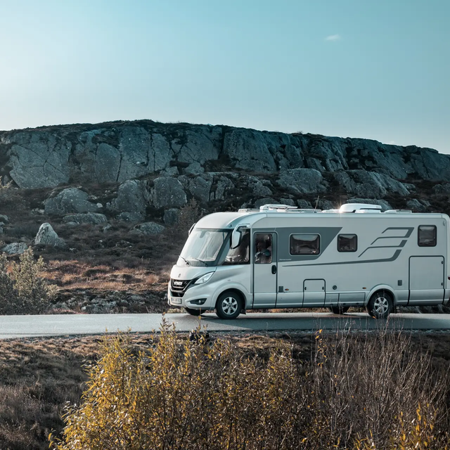 HYMER B-Klasse MasterLine vanaf de zijkant op een weg in Scandinavië met een typisch heuvellandschap aan de kant van de weg