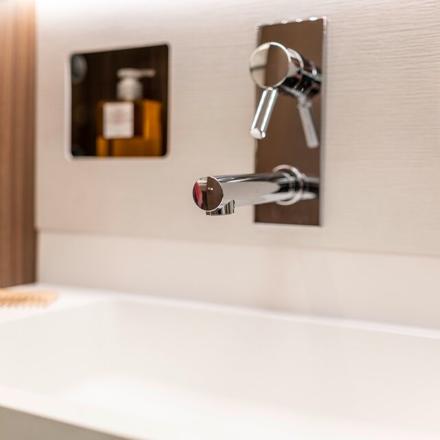 Designwastafel met geïntegreerde mengkraan, opbergnissen en wandbeslag in de salonbadkamer van de HYMER B-klasse MasterLine