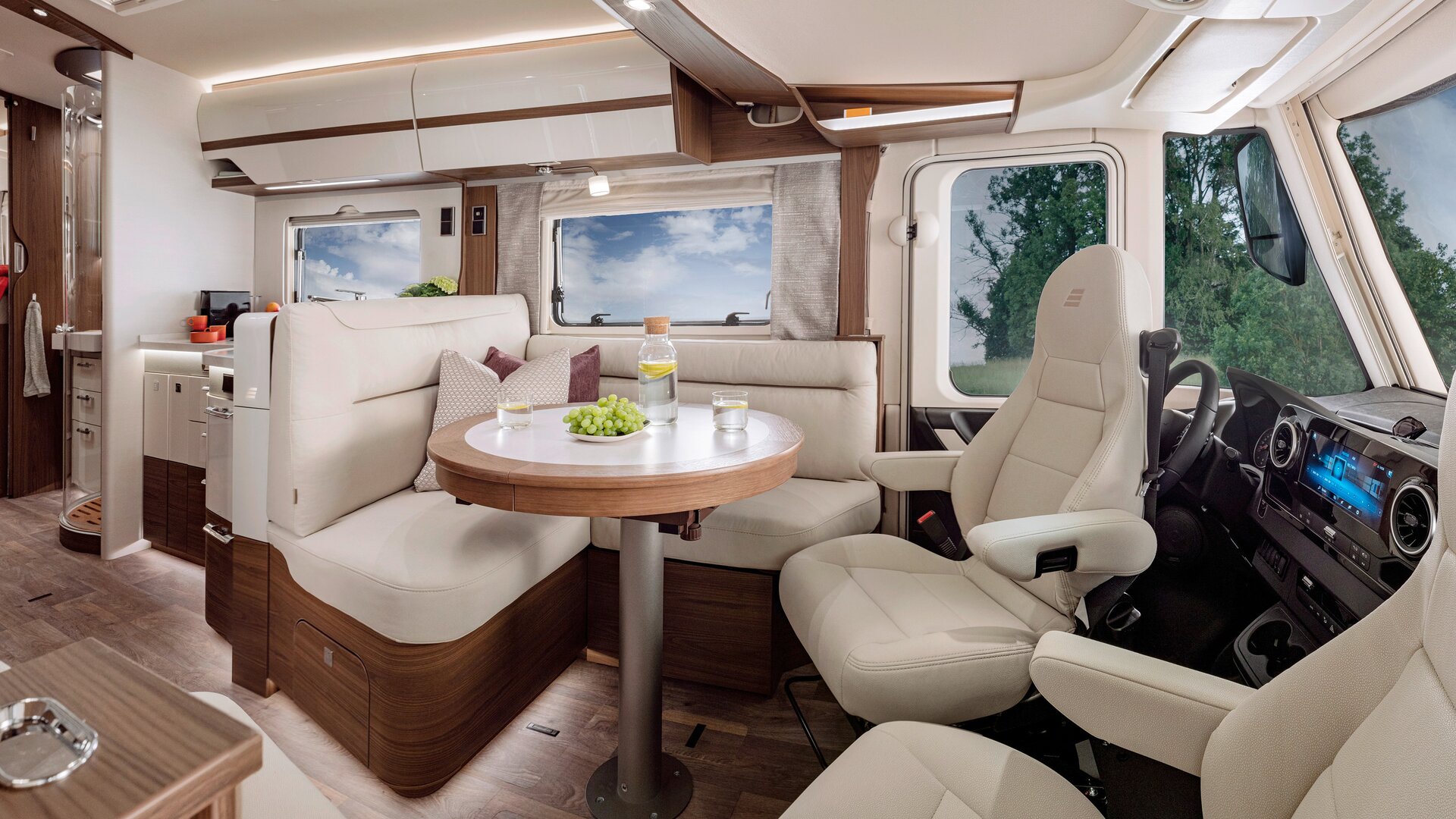 Living room in the HYMER-B-MasterLine with a round table and seating in cream-colored leather