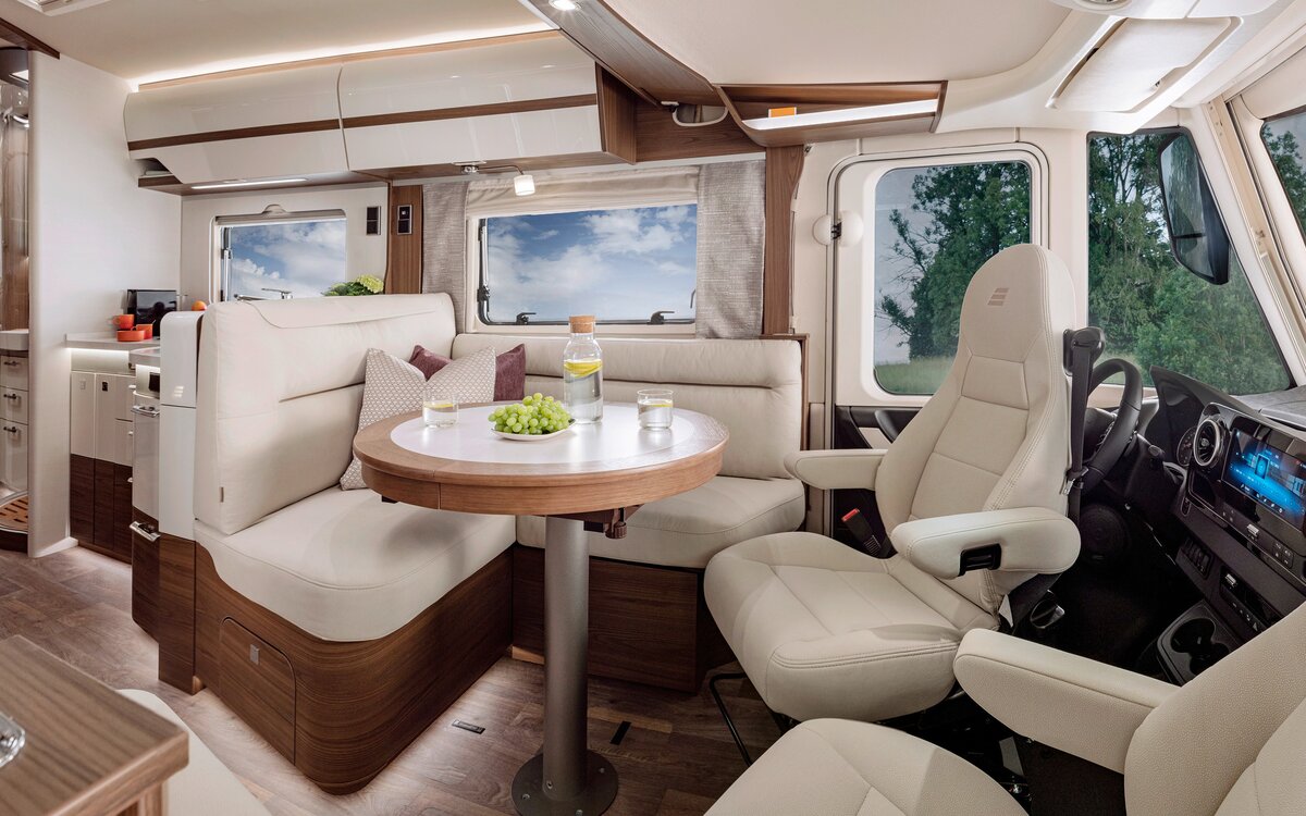 Woonkamer in de HYMER-B-MasterLine met stoelen in crèmekleurige lederlook aan de ronde tafel