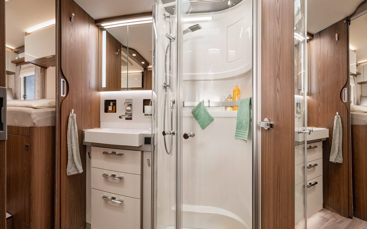 Salonbadkamer in de HYMER B-ML I 880: spiegelkast, lades onder de wastafel, aparte douche met echt glazen deuren, badkameraccessoires