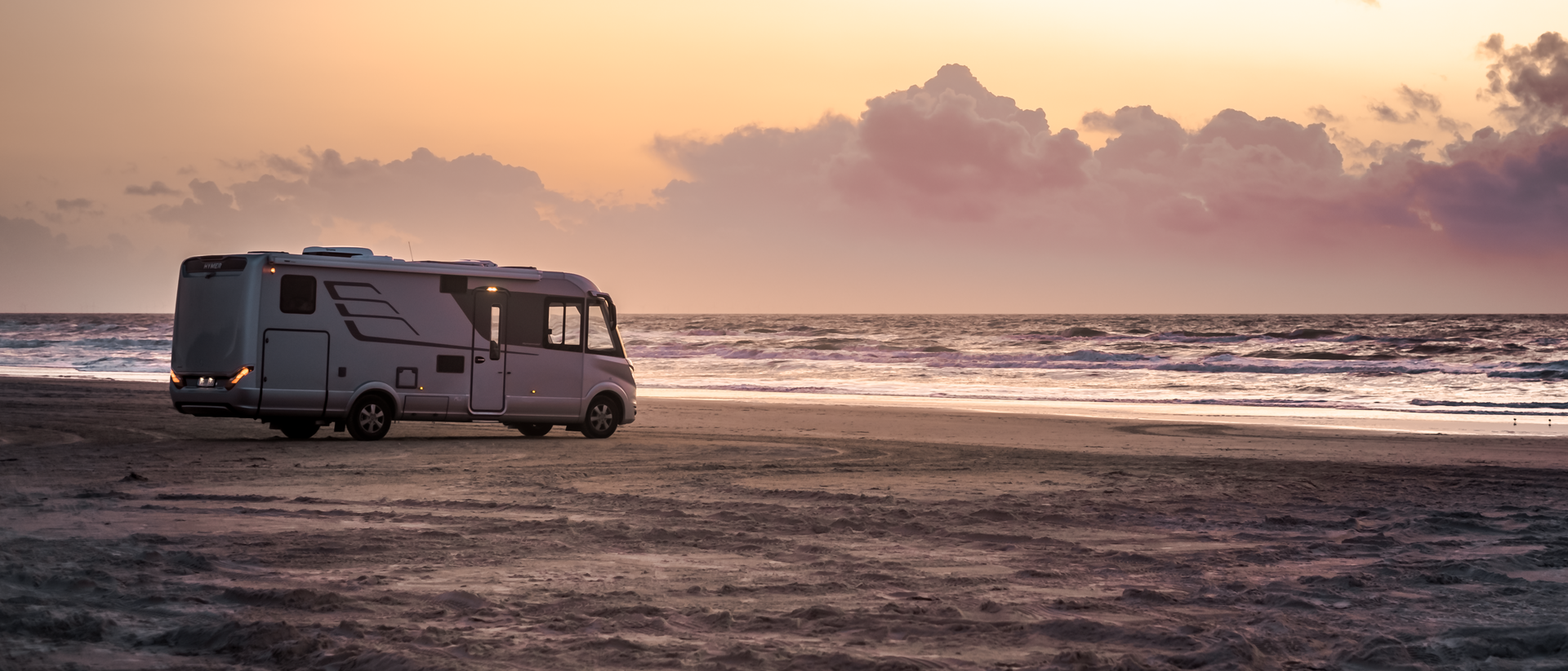 HYMER B-klasse MasterLine I aan zee op het zandstrand met zonsondergang
