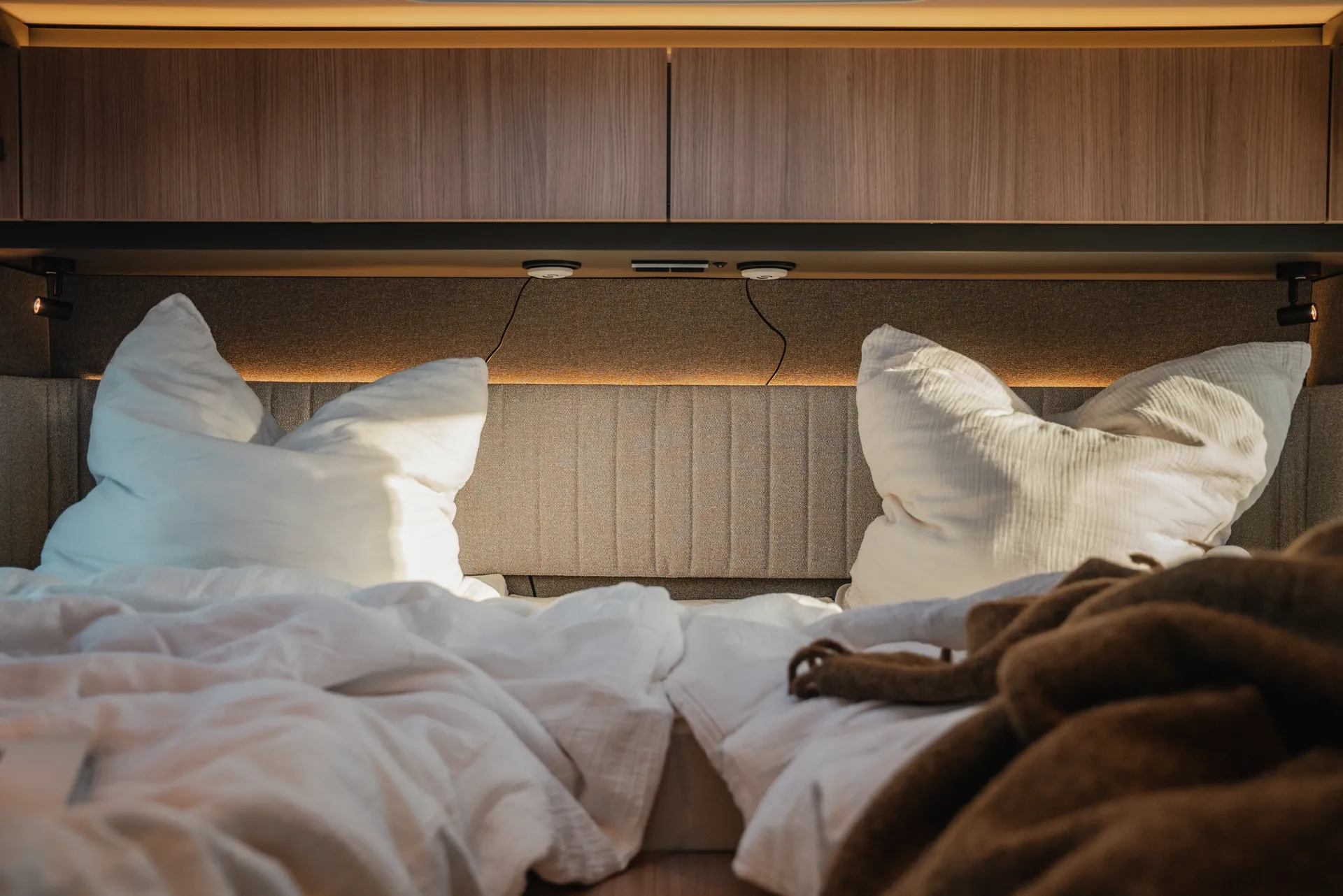Overhead lockers in premium ribbed HPL finish define the clear material language and give the sleeping area additional depth and quality.