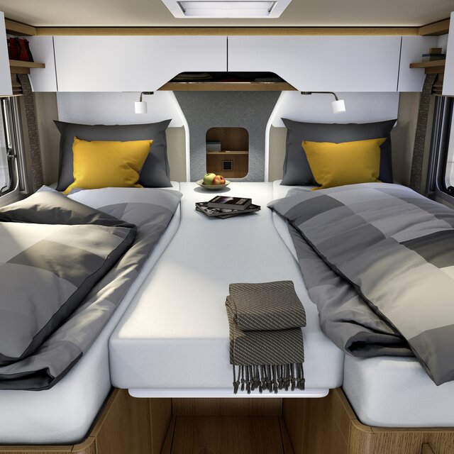 Eenpersoonsbedden in de lengte met grijs geruit beddengoed, gele sierkussens en centraal extra kussen achter in de HYMER B-ML I