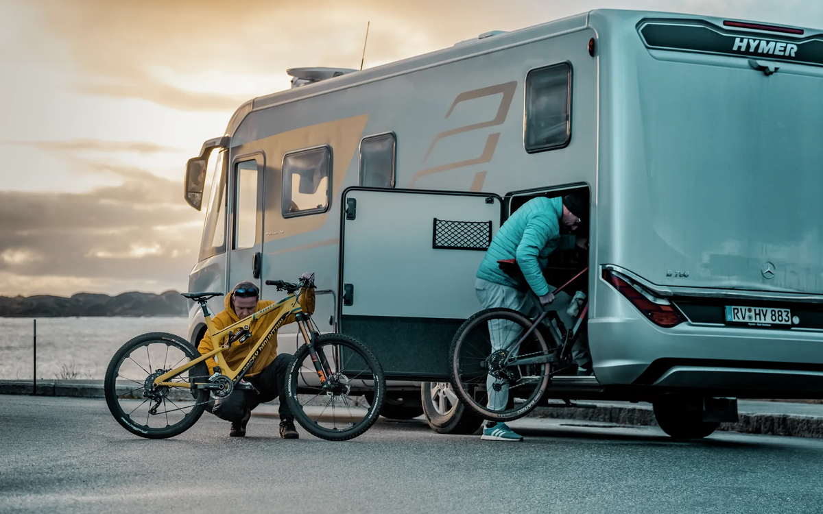 Twee mannen laden mountainbikes in de garage achter van de HYMER B-klasse MasterLine