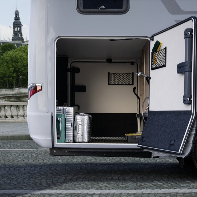 De deur van de garage achter van de HYMER B MasterLine, beladen met twee zilverkleurige koffers, is in rijrichting naar rechts geopend