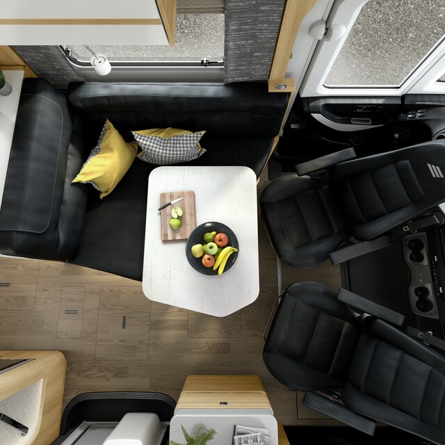 Zitgroep inclusief chauffeursstoelen in zwart lederlook met fruitschaal gedekte tafel in de HYMER MasterLine