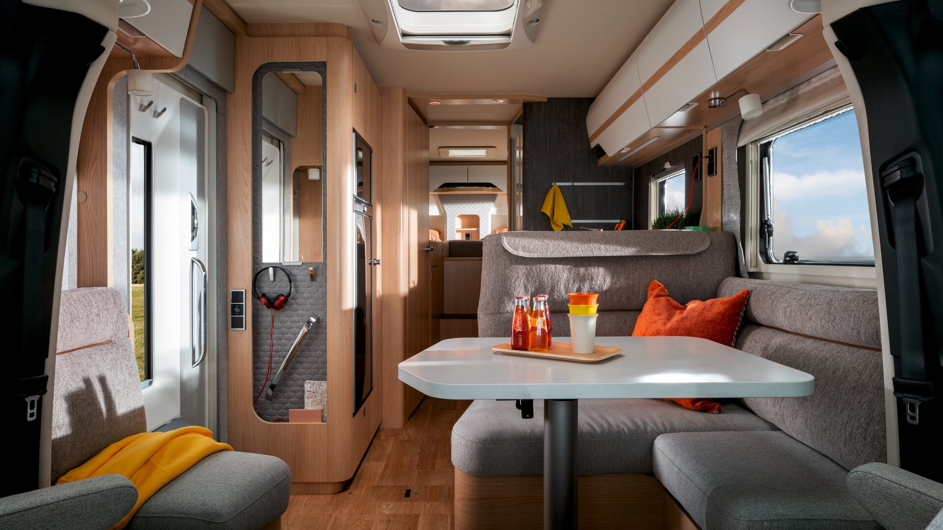 In the Mercedes Sprinter motorhome HYMER B-Class MasterLine T with a skylight, drinks and cups are placed on the table, the seating area is grey.