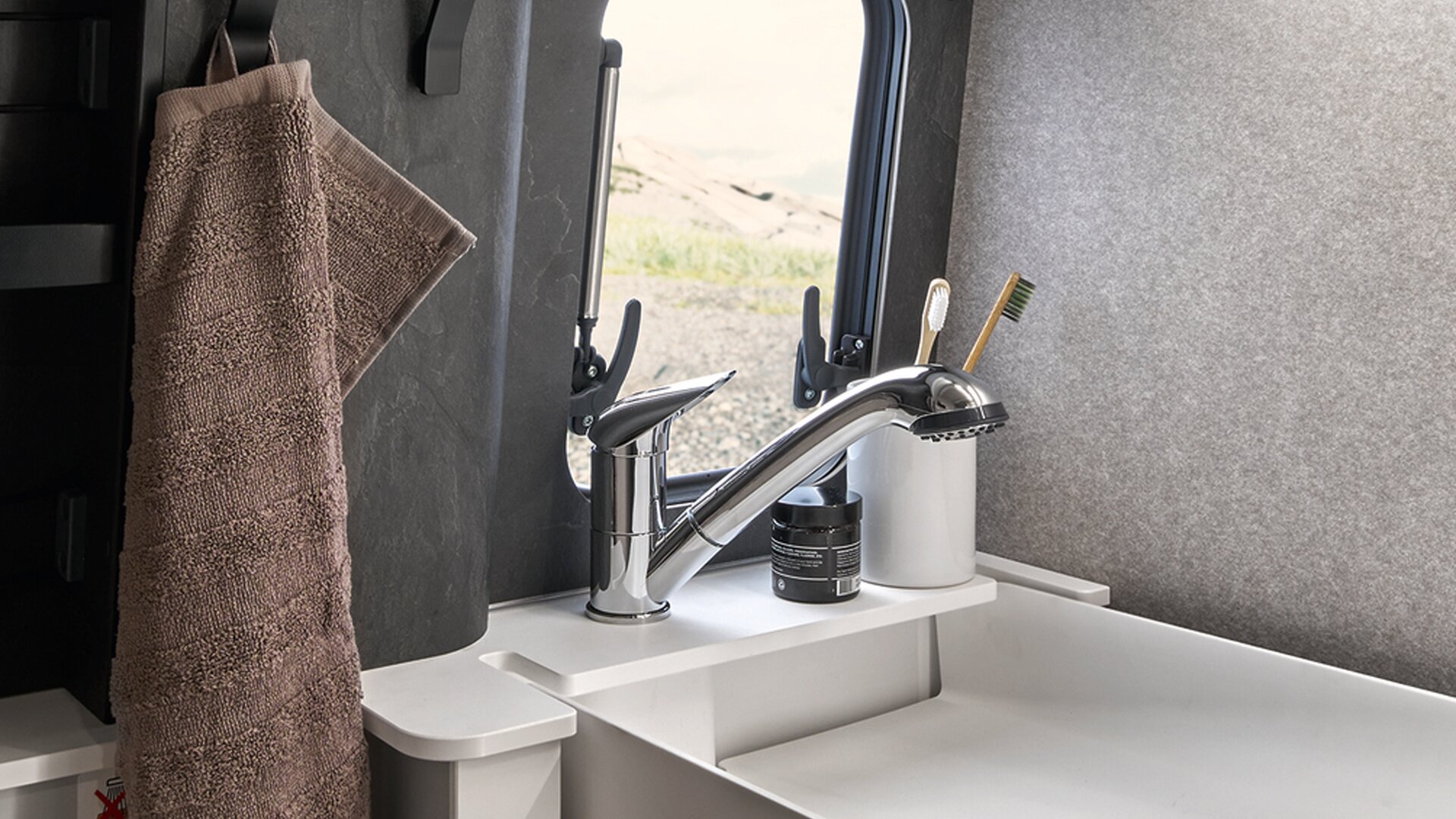 The sink of the HYMER Grand Canyon S in the folded-down state is visible, including the faucet. A towel hangs next to it.