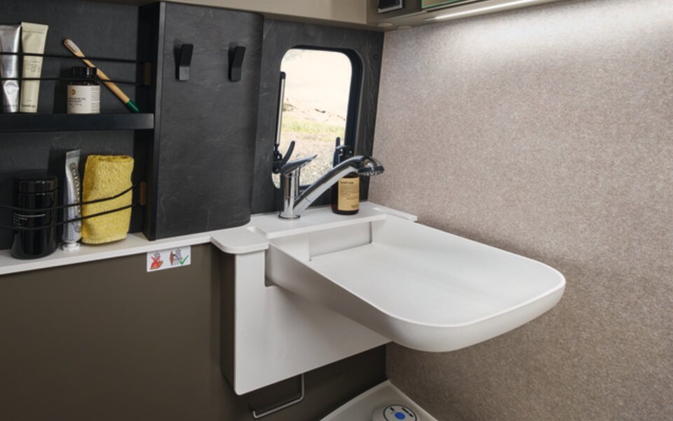 In the compact bathroom of the HYMER Grand Canyon S in the Ivy Green style world, there are numerous storage options for your toiletries.