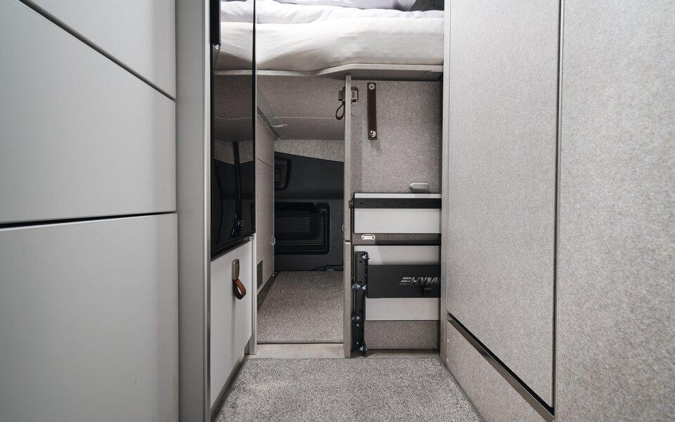 It is visible that the rear garage of the HYMER Grand Canyon S in the Pearl Grey style world is accessible from the interior of the vehicle under the bed.