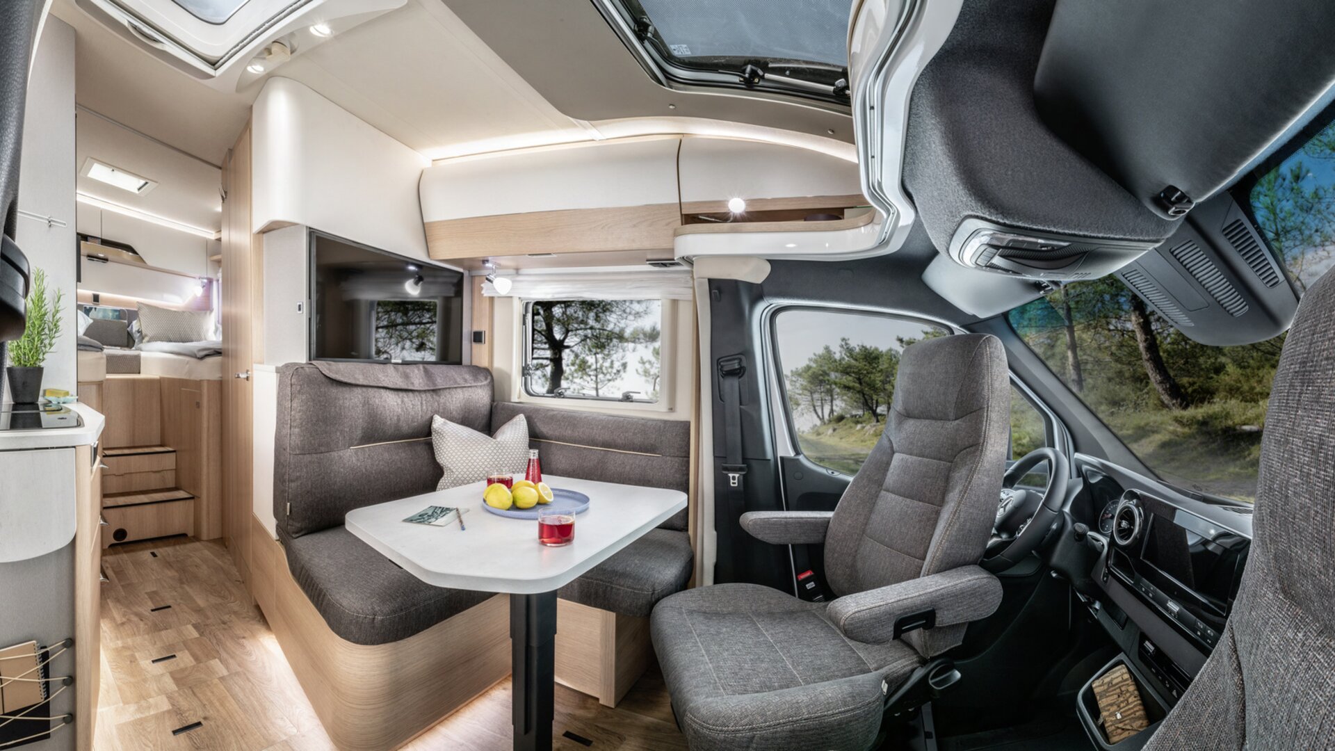 Lounge seating group with driver's cab, set table, TV plasma and kitchen in the HYMER B ModernComfort T