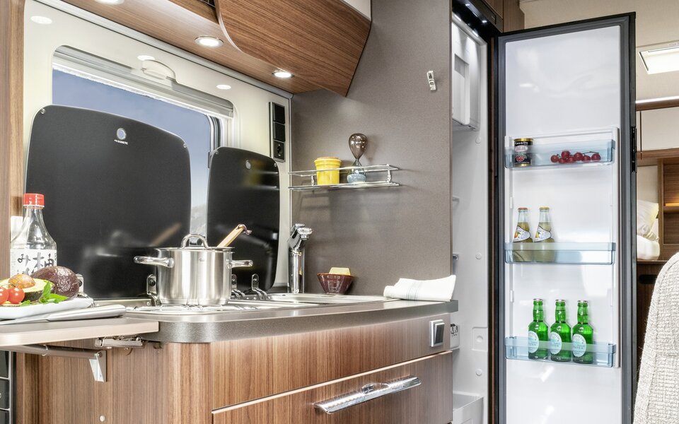 Küchenblock mit Arbeitsplattenerweiterung, Kochtopf auf dem Herd, sonstiges Küchenzubehör, offener Kühlschrank im HYMER ML-T