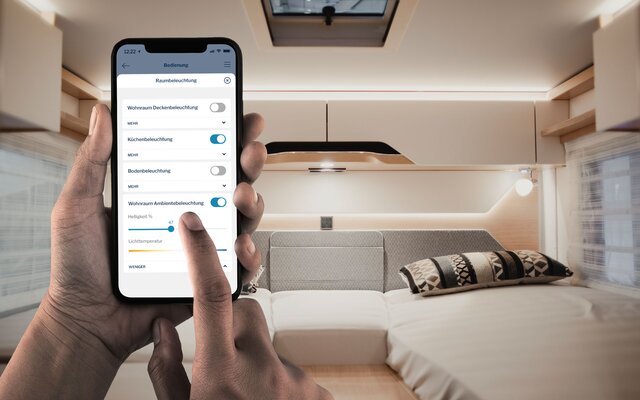 Hands of a person using a mobile phone in the rear sleeping area of a motorhome, the screen shows the use of the HYMER Connect app