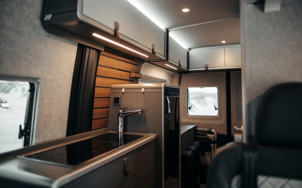 Interior of a camper van, kitchen block with fridge and light overhead lockers