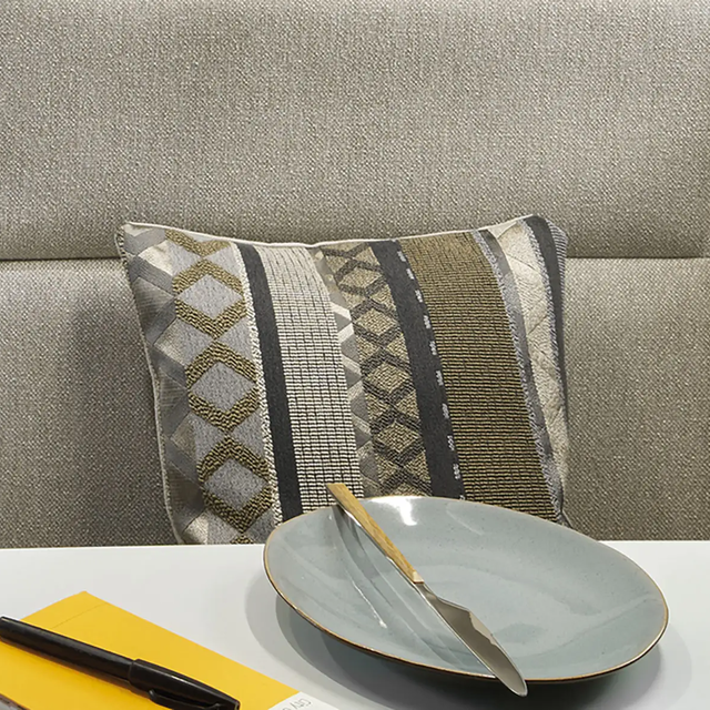 Close-up of a cushion patterned in various shades of grey, beige, and olive green.