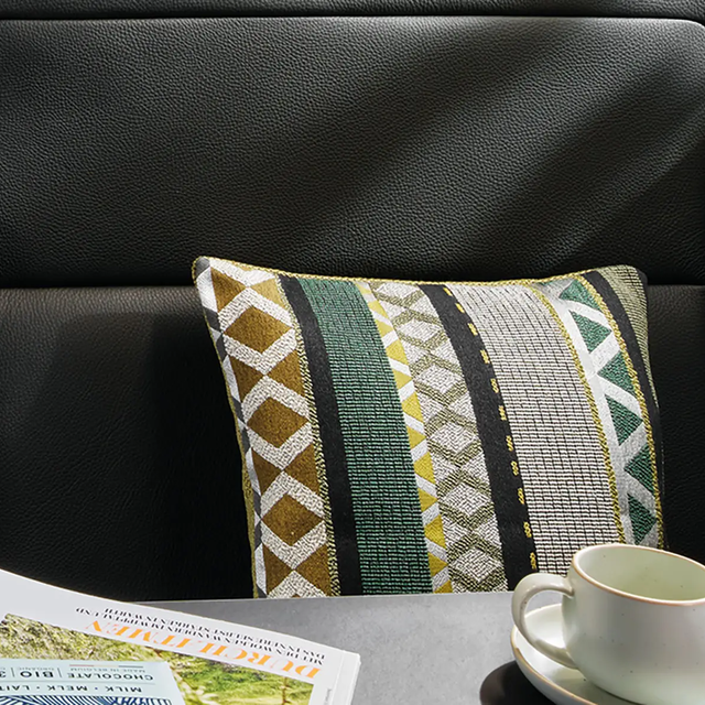Close-up of a cushion patterned in various shades of beige, green, yellow, brown, and black.