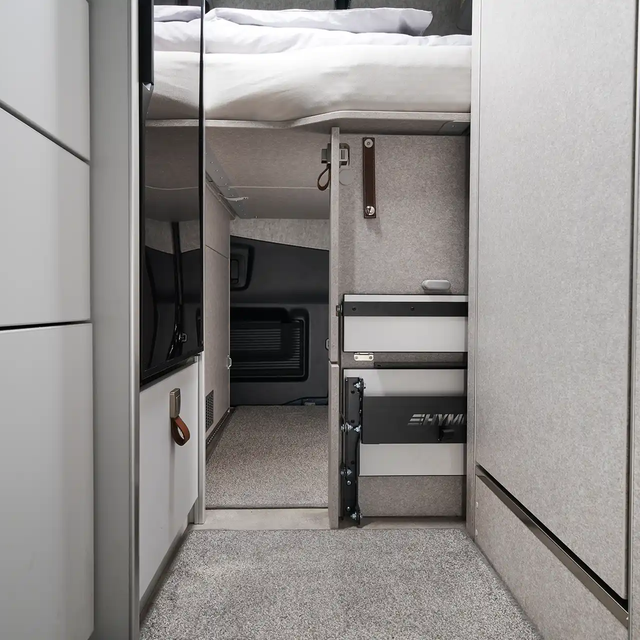 It is visible that the rear garage of the HYMER Grand Canyon S in the Pearl Grey style world is accessible from the interior of the vehicle under the bed.