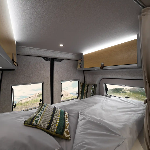 The sleeping area of the Grand Canyon S in the Pearl Grey style world is visible from the kitchen. The duvet has a grey cover.