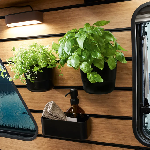 Herb pots and a container are mounted on the multifunction wall in the Magic Diner of the HYMER Venture S.