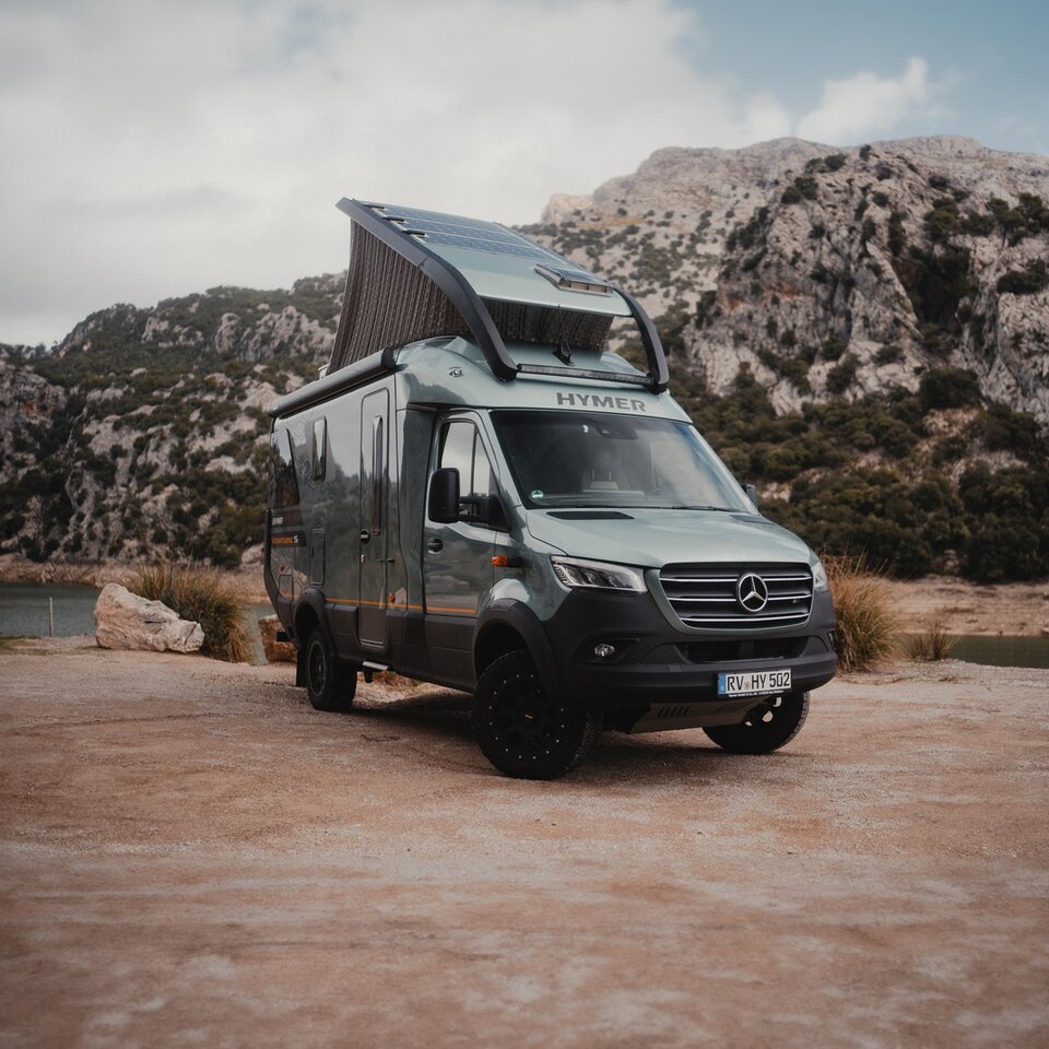 Utsikt från bakre sidan av Venture S, med taket och Sunset Deck utfoldat, med fjell och vatten i bakgrunden.